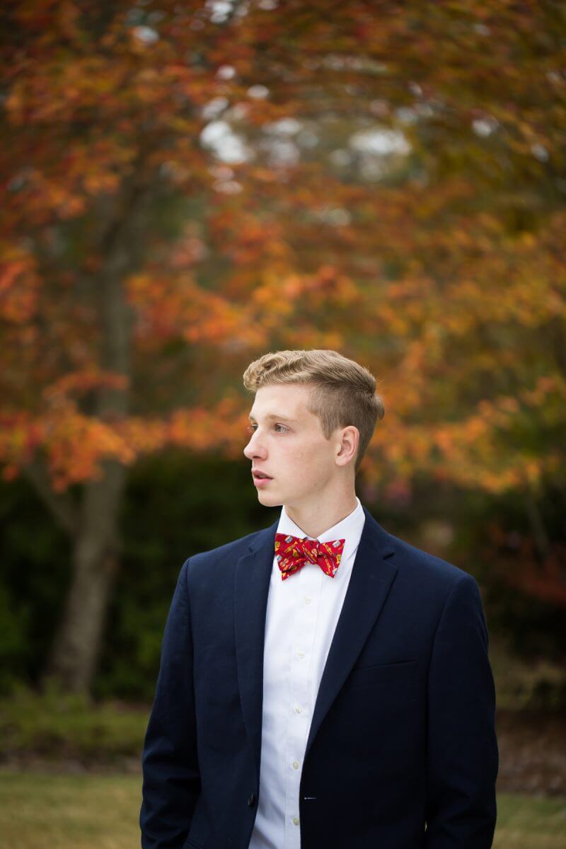 high school senior portrait young man in profile in front of fall trees