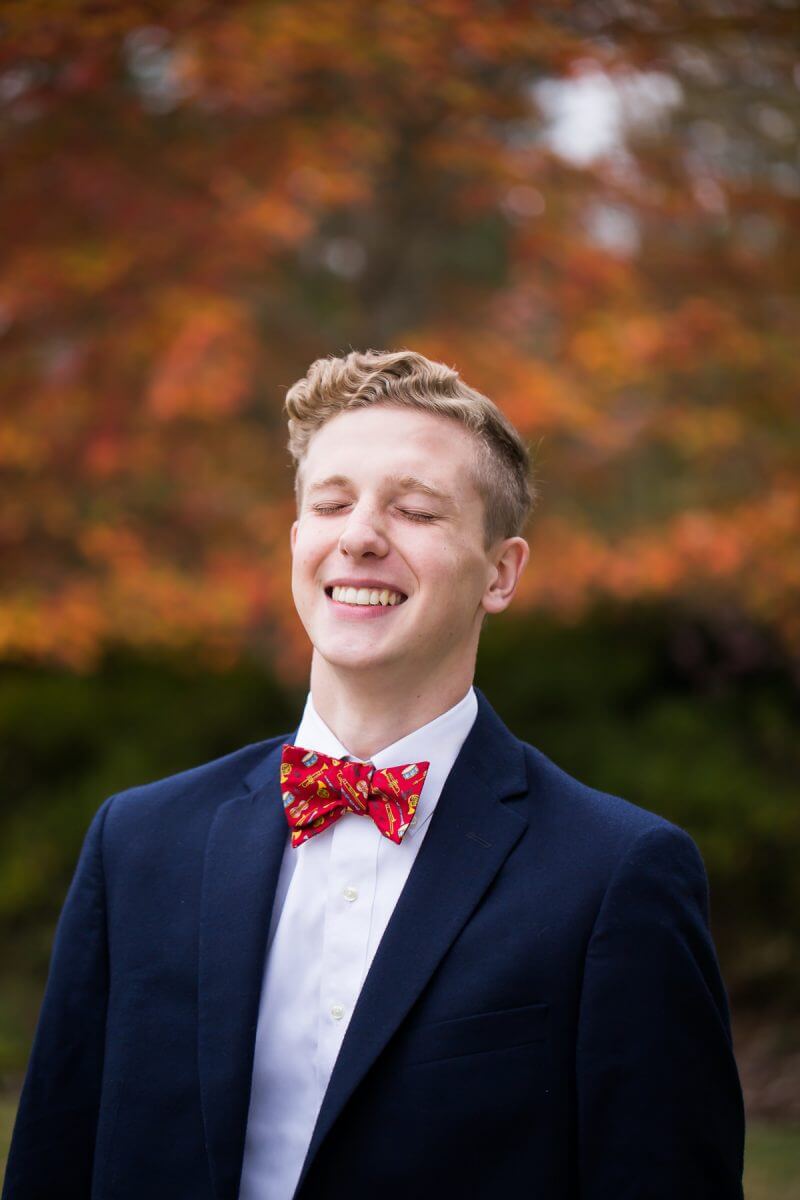 laughing high school senior young man in sport coat and bow tie