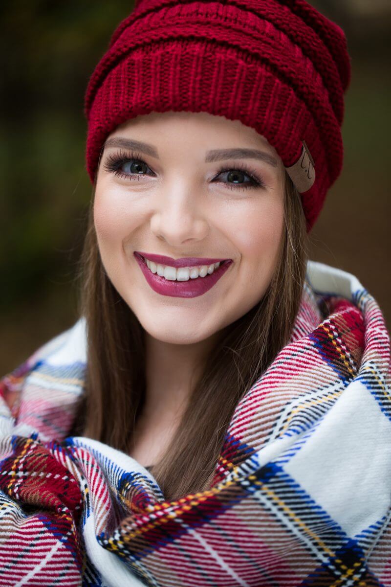 smiling brunette senior portrait in red beanie