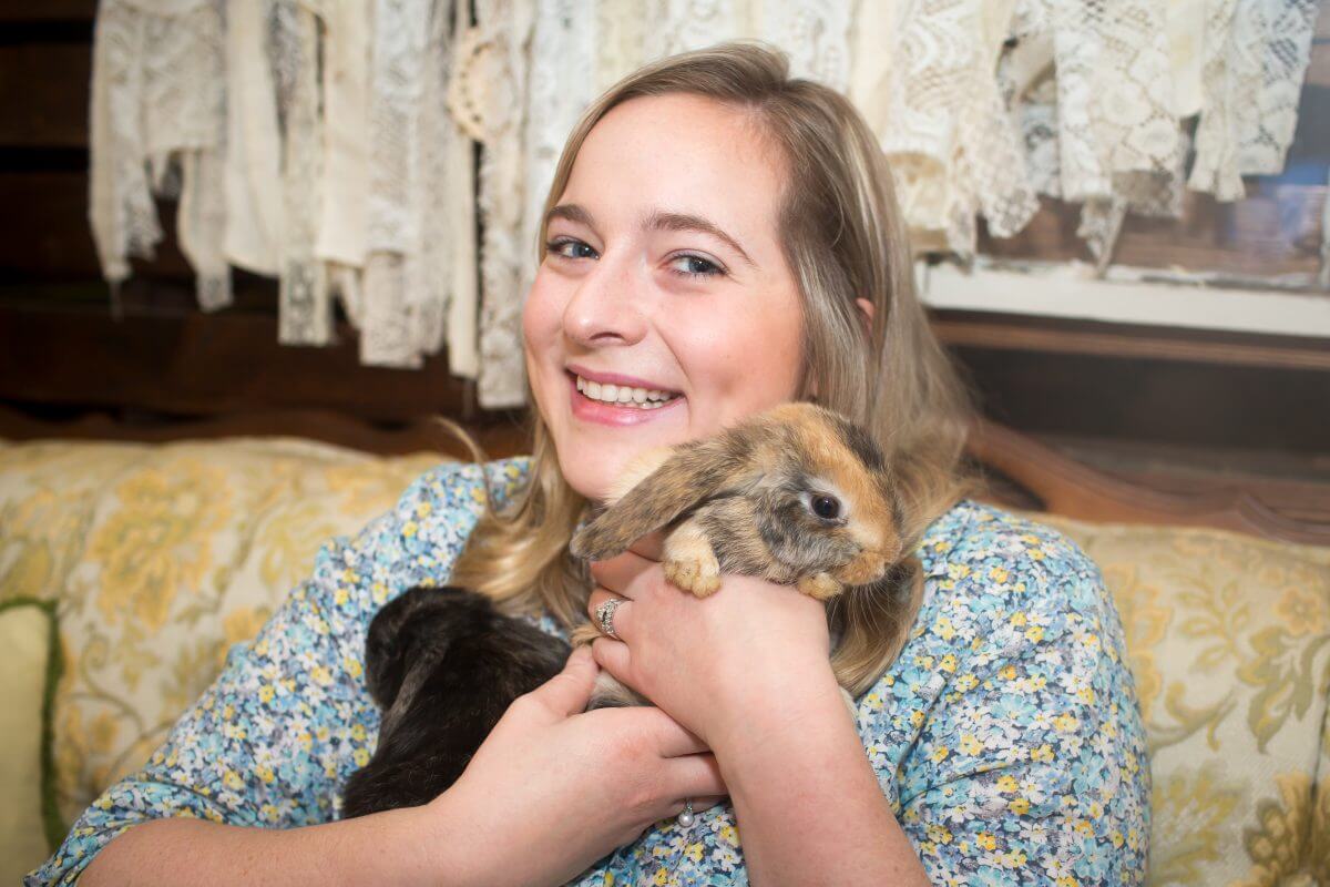 Blonde woman snuggles with black rabbit and tan rabbit for Easter photo