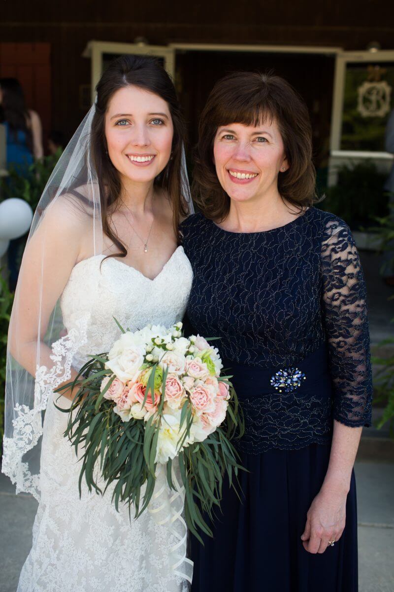smiling bride with bouquet posing with mother at ruston, louisiana wedding