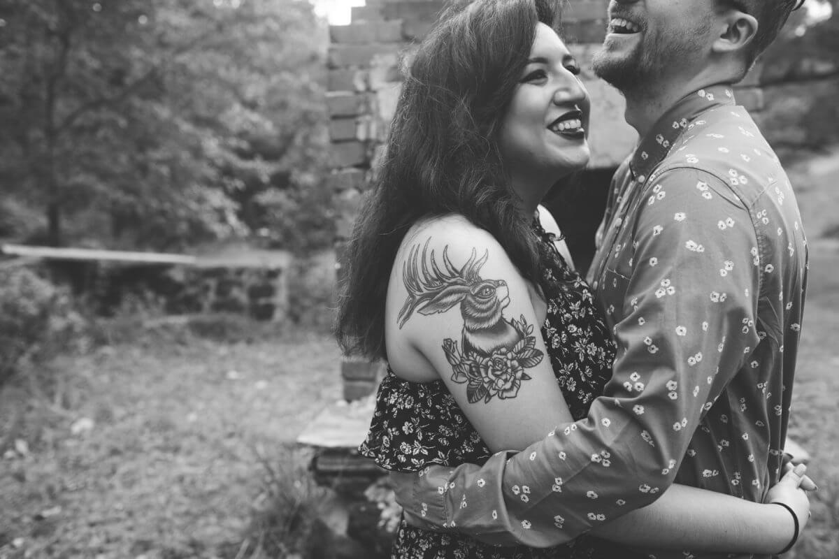 smiling woman with tattoo hugging laughing man in black and white
