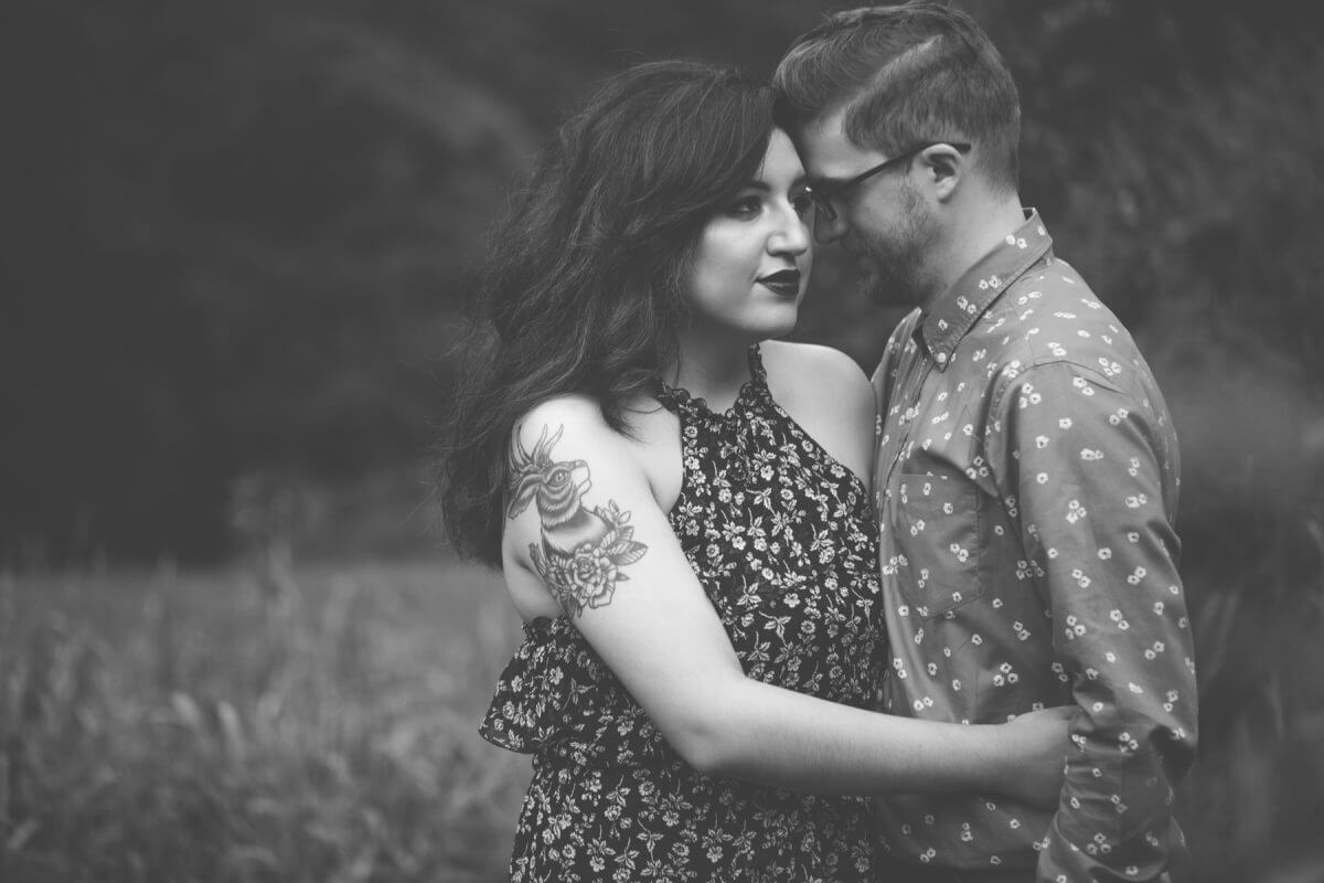 engaged couple with foreheads together posing in black and white