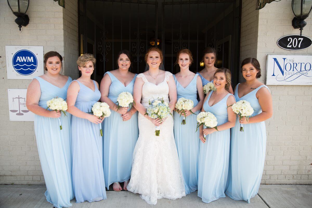 bride in wedding dress with brides maids in blue dresses in front of Norton Building in Ruston, LA
