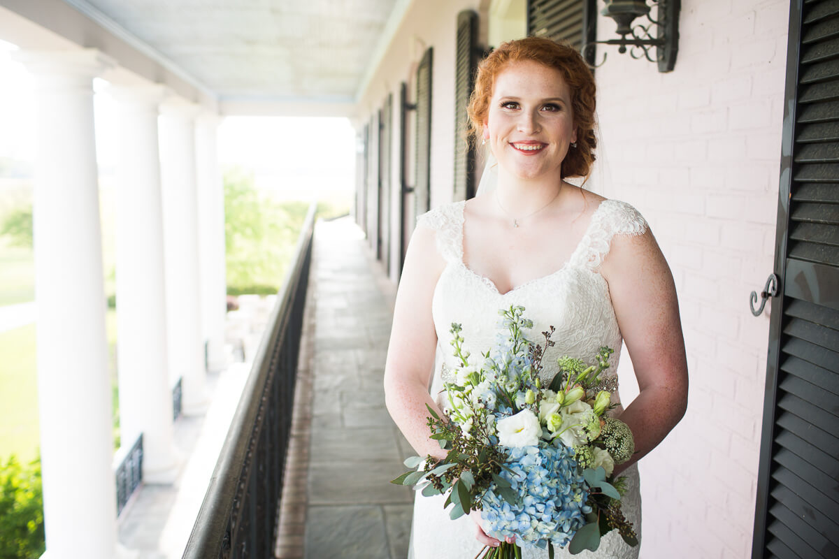 redheaded bride with bouquet standing on the balcony at the Mansion at Red Hill