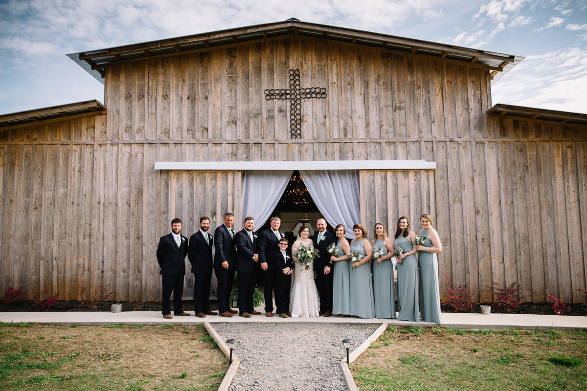 wedding party standing outside the front door of the Meadow Wedding Barn in Eros, Louisiana